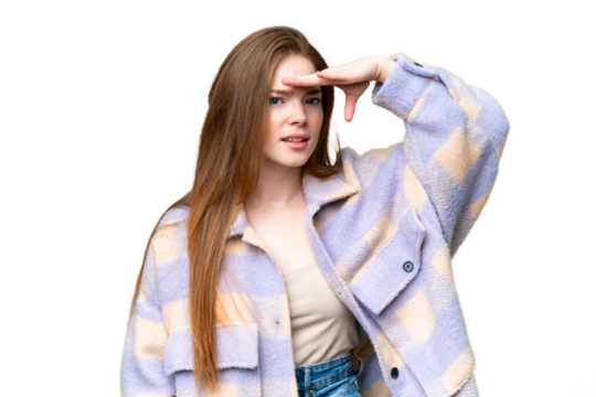 Young pretty woman over isolated chroma key background looking far away with hand to look something