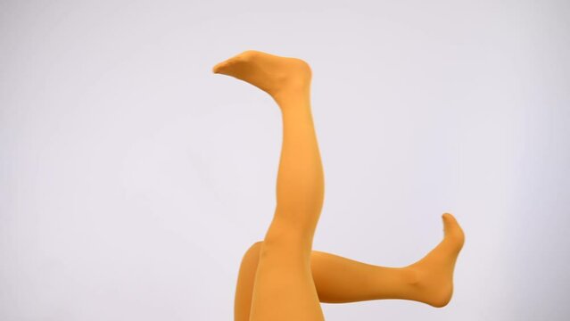 Female legs in ocher tights on a white background. Copy space. 