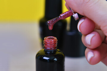 shiny red gel polish dripping from a brush close-up