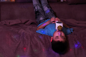  boy lies head down on the sofa and sings into the microphone