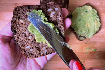 applying avocado paste to a piece of bread