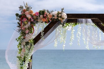 Wedding arch decorated with flowers on the beach