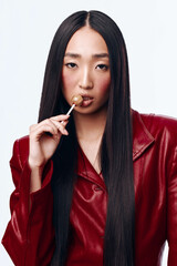 Beautiful young woman with long black hair and red jacket enjoying sweet candy treat