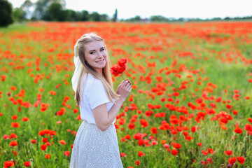 portrait of romantic girl in a white dress in a field with red poppies