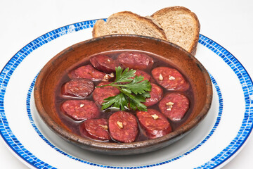 Chorizo ​​in red wine, dish of chorizo ​​cooked in red wine accompanied by bread, Traditional Spanish tapas dish.
