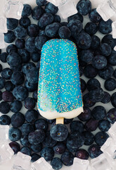 Summer layout made with blue glazed ice cream popsicle, fresh blueberries and ice cubes on white background. Minimal summer creative concept. Fruit and candy flat lay composition.