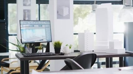 Designing office has empty desk with computer operating cad, production layouts and blueprints on...