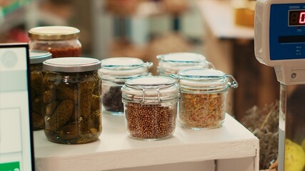 Cereals and grains in reusable jars placed on checkout counter at local eco supermarket, low carbon...