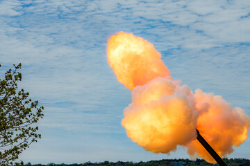 A piece of artillery fires a shell. A large plume of flame and smoke explodes from the end of the barrel.