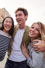 Vertical. Multiracial young people hugging together outdoor, diverse students and friends laughing....