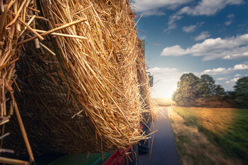fahrzeug mit strohballen auf einer straßen unterwegs zum bauernhof im sonnenschein