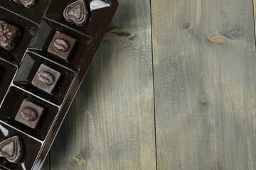 Chocolates in a box How to choose horses. Day chocolate candy background on wooden grey black...