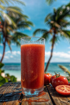 A glass of fresh tomato juice on a paradise beach.