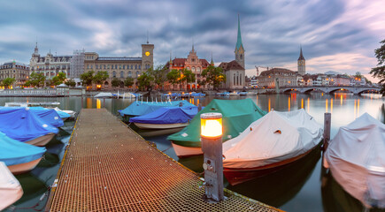 Panoramic view of Zurich dock on Limmat River with boats and Fraumunster at dusk, Switzerland