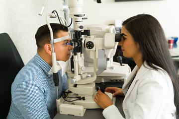 Profile view of an ophthalmologist using a slit lamp to examine a male patient's eyes in a modern...