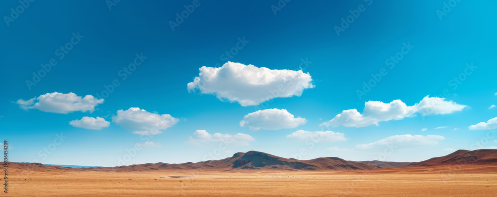Wall mural vast desert landscape with mountains under a bright blue sky and scattered clouds. nature and wilder