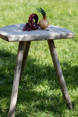Red dried hot pepper and onion head with green fins on wooden background. Blurred green background.
