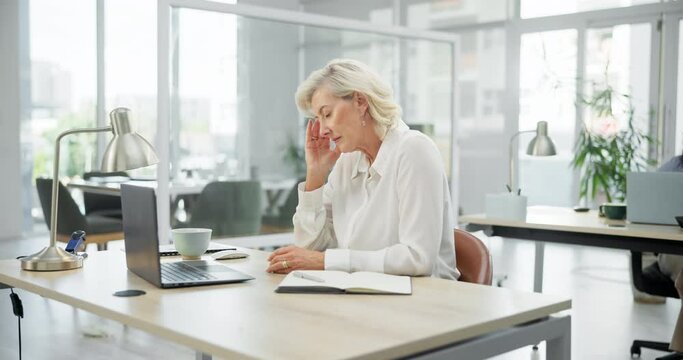 Mature woman, frustrated and debt with headache in burnout, stress or anxiety at office desk. Tired female person or employee with migraine from deadline, financial crisis or bankruptcy at workplace