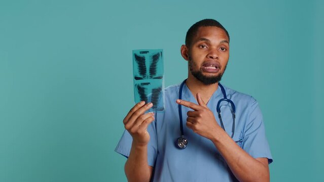 Healthcare professional informing patient of radiology x ray scan results, studio backdrop. African american doctor presenting radiography and providing injury treatment, camera A