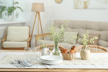 Clean dishes, flowers and fresh pastries on table in stylish dining room