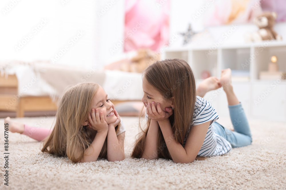 Wall mural Cute little sisters on floor at home