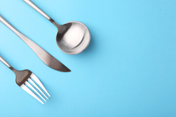 Stylish cutlery set on light blue table, flat lay. Space for text
