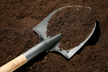 Metal shovel on fertile soil. Gardening tool