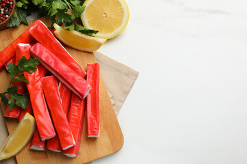 Tasty crab sticks, parsley and pieces of lemon on white table, flat lay. Space for text © New Africa