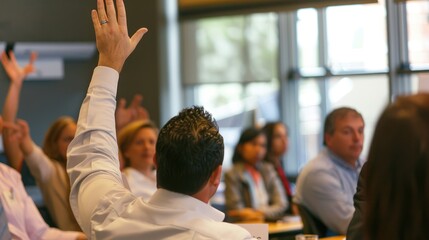 People are sitting in a room with their hands raised, waiting to be acknowledged to speak. AIG535