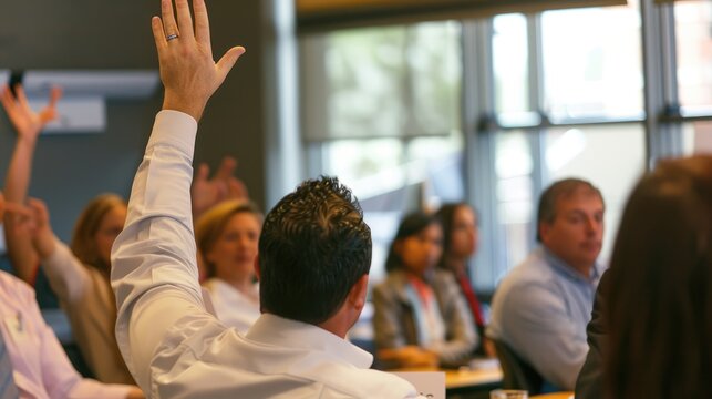 People are sitting in a room with their hands raised, waiting to be acknowledged to speak. AIG535