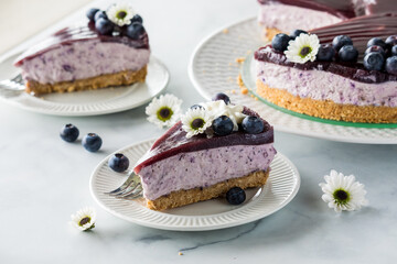 Slices of fresh creamy blueberry cheesecake, topped with fresh berries.