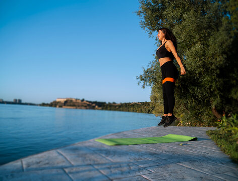 Energetic girl exercising outdoors in the middle of the jump, burpee