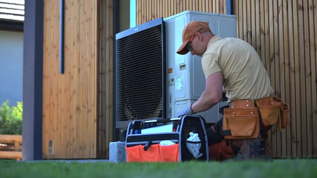 Technician Inspecting Outdoor Heat Pump Unit