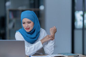 Cheerful muslim lady wear hijab working in the office, using laptop, Side view of smiling arab woman, freelancer typing on laptop, Muslim working woman concept.