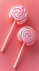Two pink and white swirl lollipops on pink background. Sweet treats and candy concept