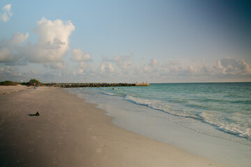 Wide angle Low view of Pass-s-grille beach in St. Pete Beach Florida looking south. Near sunset blue water with ripple waves and white clouds.