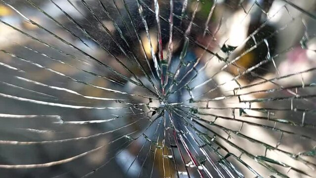 Ventana quebrada, rota o estrellada con la vista desenfocada del movimiento de las calles como negocios, se&ntilde;alizaciones, transe&uacute;ntes y automoviles.