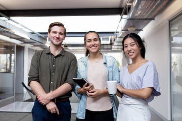 Three businesspeople smiling at the camera in an office