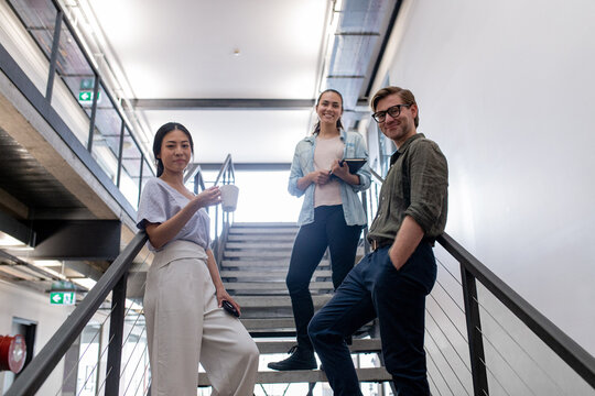 Three designers standing on office stairs in an industrial office space