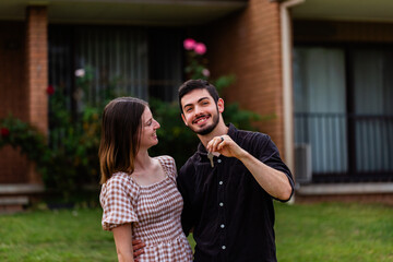 Young first home buyers in their twenties with keys to unit house
