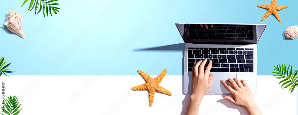 Poster person using a laptop computer with summer theme objects - flat lay
