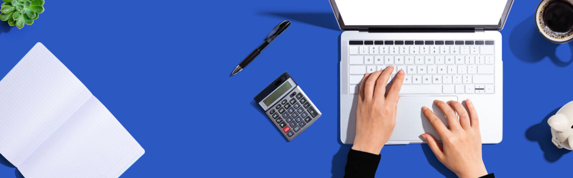 Woman using a laptop computer with a piggy bank and a calculator