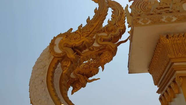 Church fence with three-headed Naga statue  Open a mighty golden mouth  The body is white with gold trim.  Decorated with delicate Thai patterns.  Crooked body