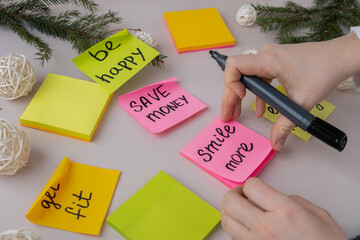 Unrecognizable woman writing new year's resolutions on colorful sticky notes. Making promises for...
