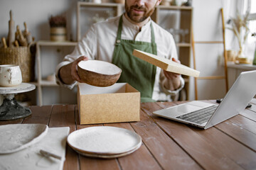 Entrepreneur sells dishes, plates and cups made of clay, ceramics online and packs them in boxes...