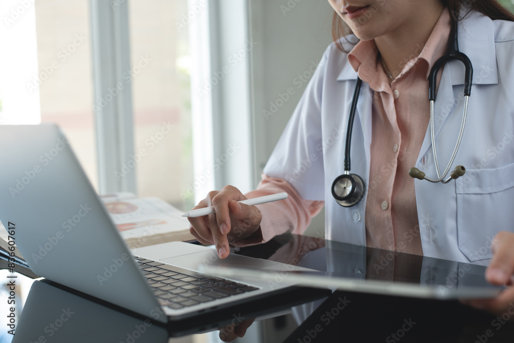 Aufkleber female doctor working on laptop computer searching the information and using digital tablet at docto