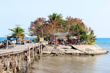 Wooden pier on tropical island leads to rustic beachfront for tranquil getaway in exotic paradise