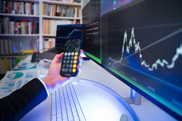 Businessman holding calculator. Financial results stock market. Monitors displaying graphs. Home...