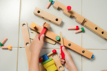 children hands playing with colorful wooden constructor puzzle bricks