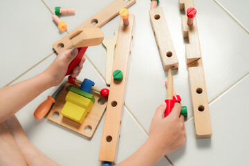children hands playing with colorful wooden constructor puzzle bricks